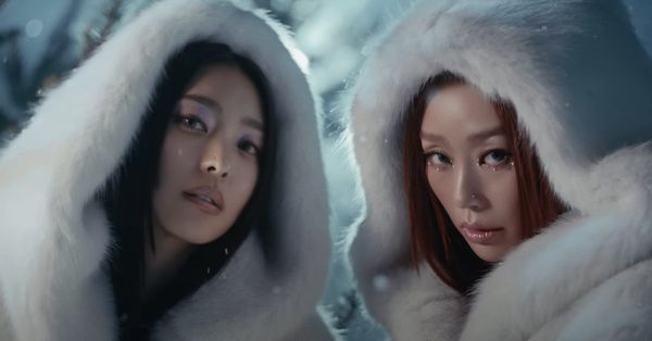 SISTAR's Bora and Hyolyn glad in white fur hoods staring at the camera in a snow-filled field.