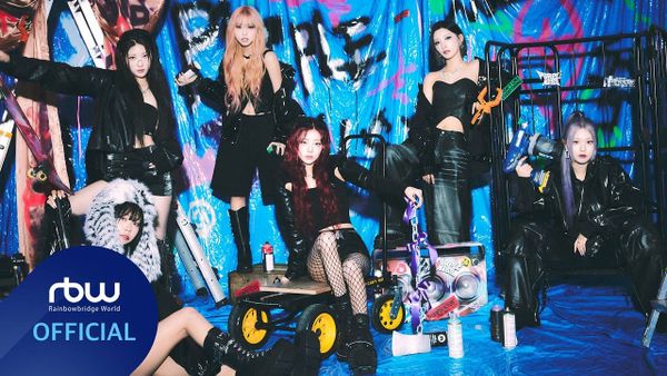 Members of Purple Kiss pose for the camera dressed in black against a brightly-colored graffiti background.