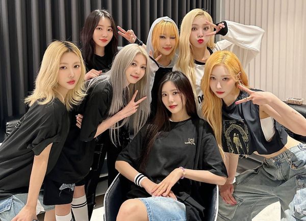Dreamcatcher dressed in black tour s-shirts and casual wear smiling and showing victory signs at the camera.
