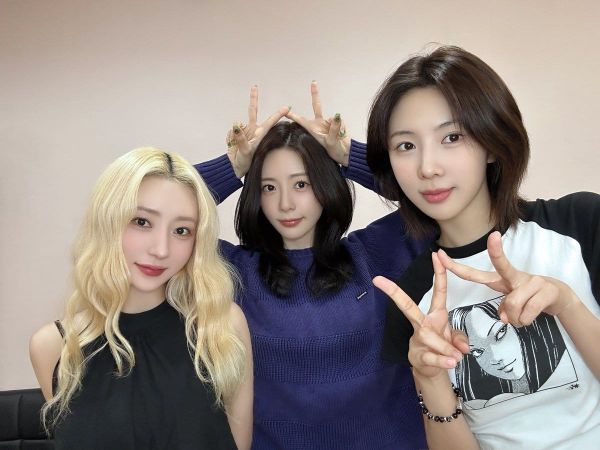 JiU (in blue), SuA (in black), and Yoohyeon (in white) taking a picture at a fansign, holding up victory signs.