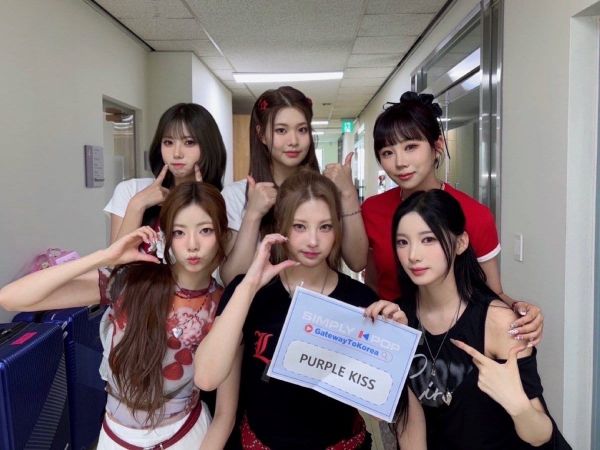 Members of Purple Kiss smile and form hearts and poses for the camera.