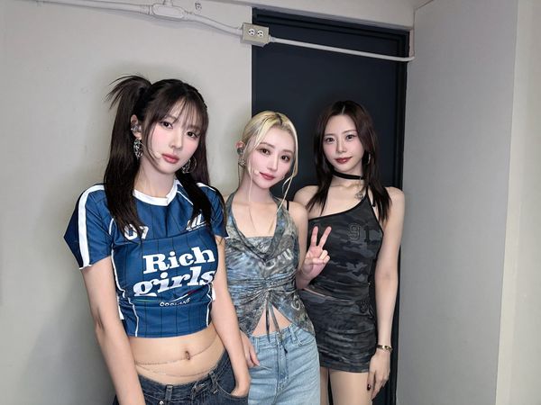 UAU members Yoohyeon SuA and JiU pose for the camera wearing casual clothes and smiling.