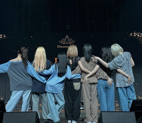 Dreamcatcher with their backs to the camera looking at their stage logo LED.
