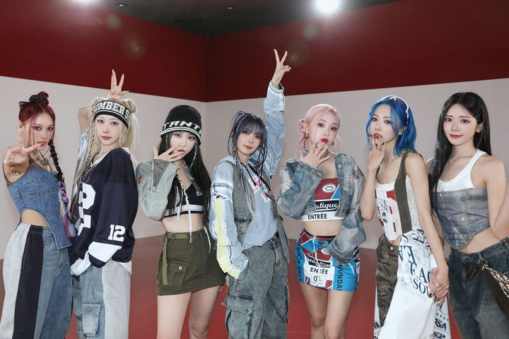 Dreamcatcher in fashionable multi-colored denim and casual clothes in front of a striped wall.