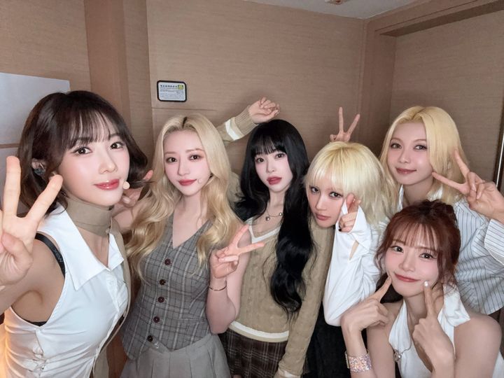 Dreamcatcher poses for the camera in a dressing room with victory signs and smiles.