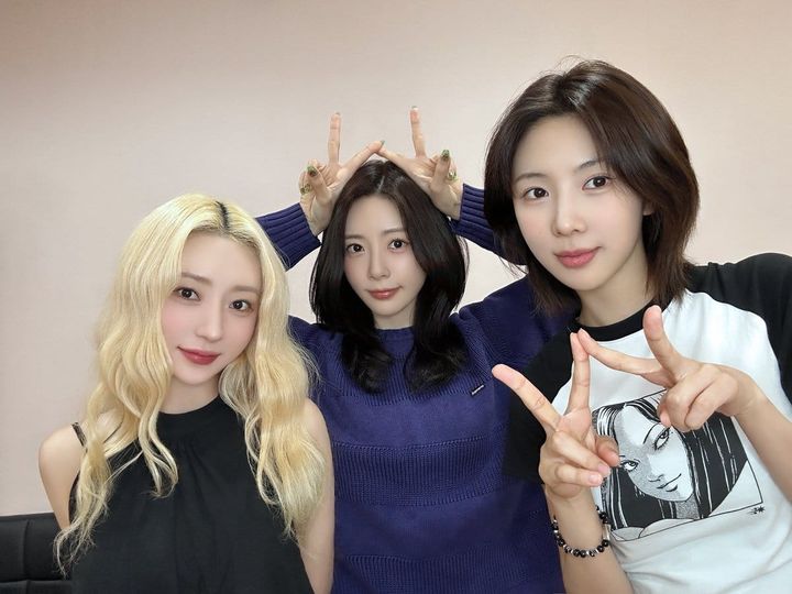 JiU (in blue), SuA (in black), and Yoohyeon (in white) taking a picture at a fansign, holding up victory signs.