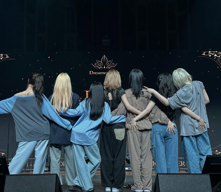 Dreamcatcher with their backs to the camera looking at their stage logo LED.