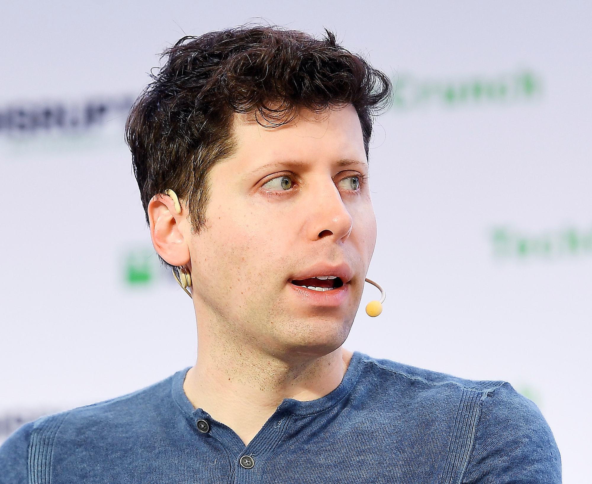 Sam Altman on stage with a headset