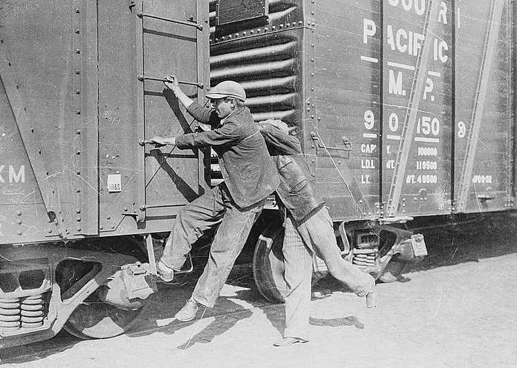 Kids hanging onto side of a train.