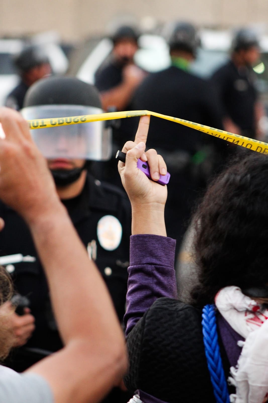 Woman giving the finger, said finger holding up yellow police tape