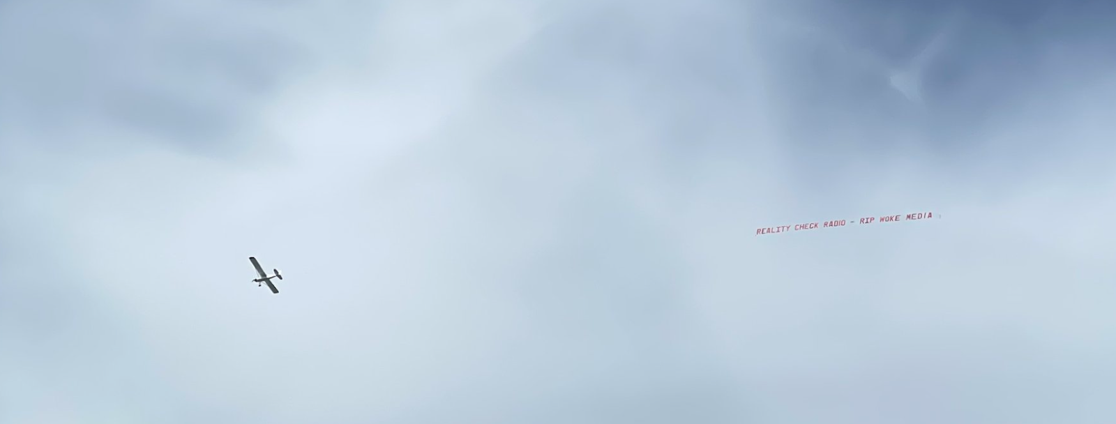 A plane in the sky trailing some kind of message behind it