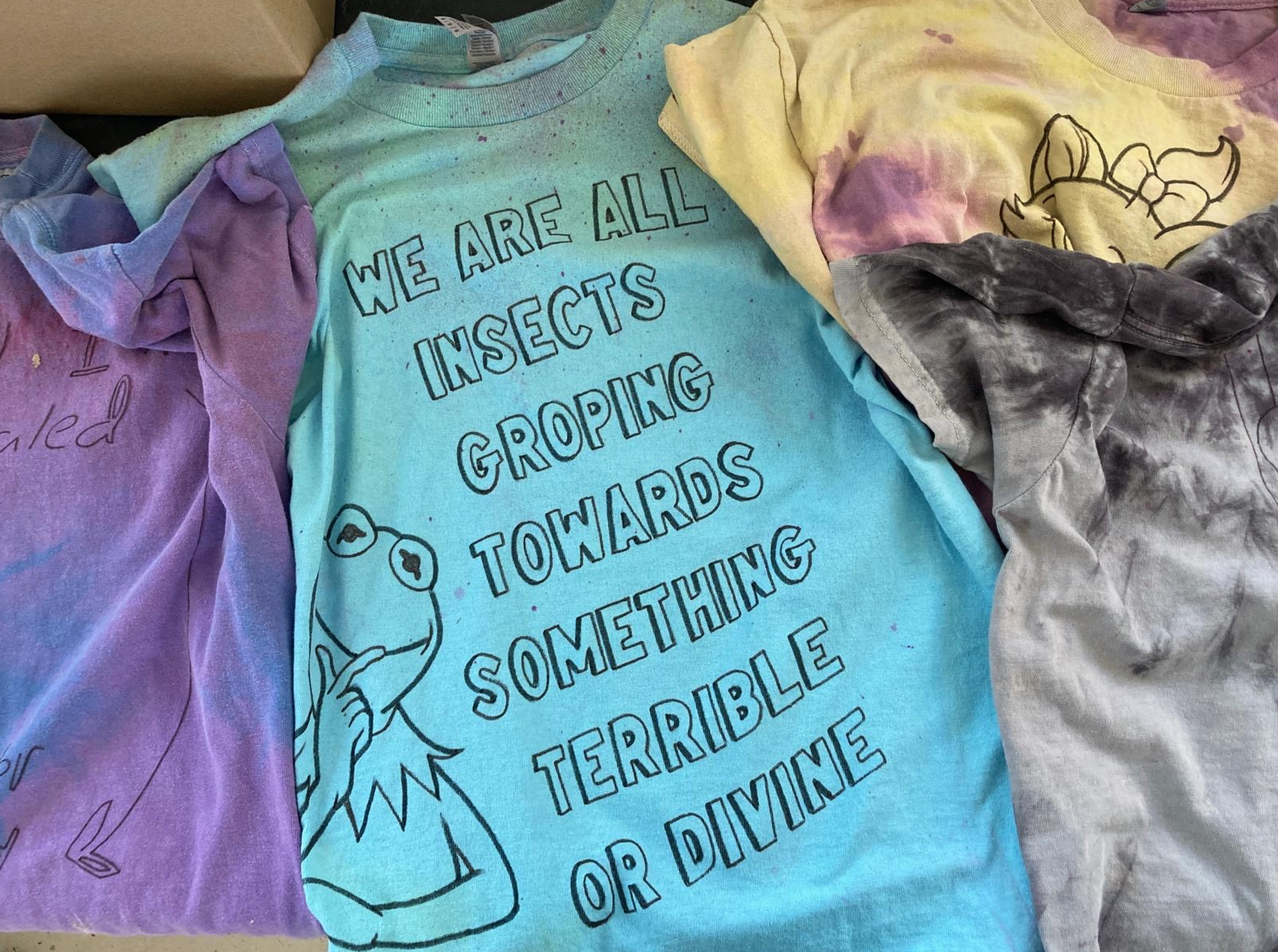 Text on shirt saying "We are all insects groping towards something terrible or divine"