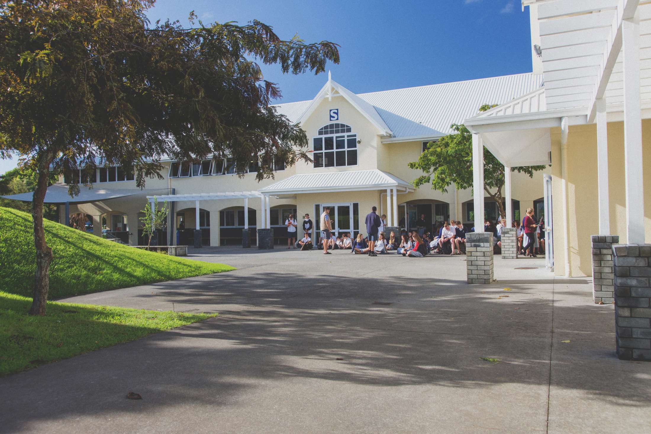 A sunny day, blue skies, students gathered outside on the concrete