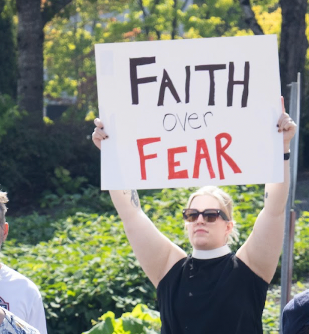Pastor holding up a "Faith Over Fear" sign