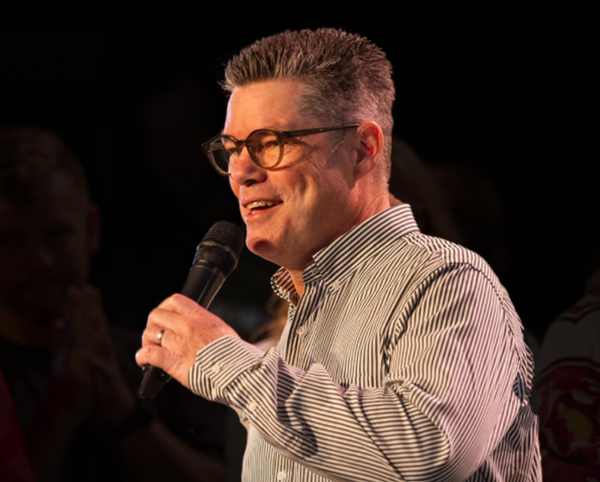 Brent Cameron holding a mic on stage