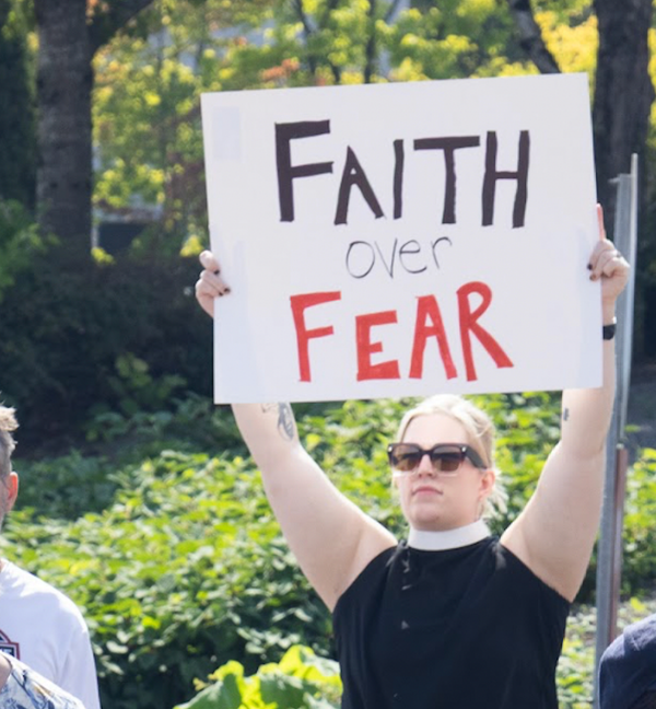 Pastor holding up a "Faith Over Fear" sign