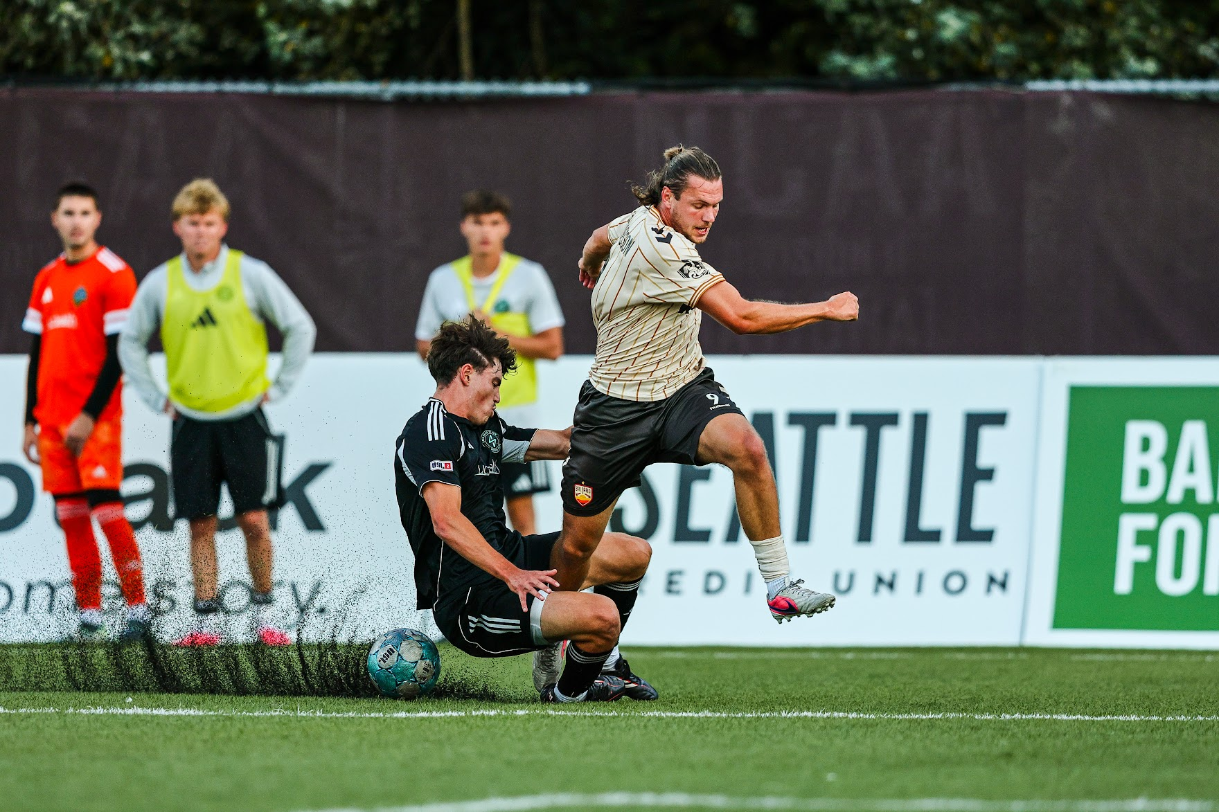 Ballard FC midfielder Anton Hjalmarsson leaps over a sliding challenge from a Colorado Storm defender during the Bridges' 4-3 USL League Two Western Conference semifinal victory at Interbay Stadium.