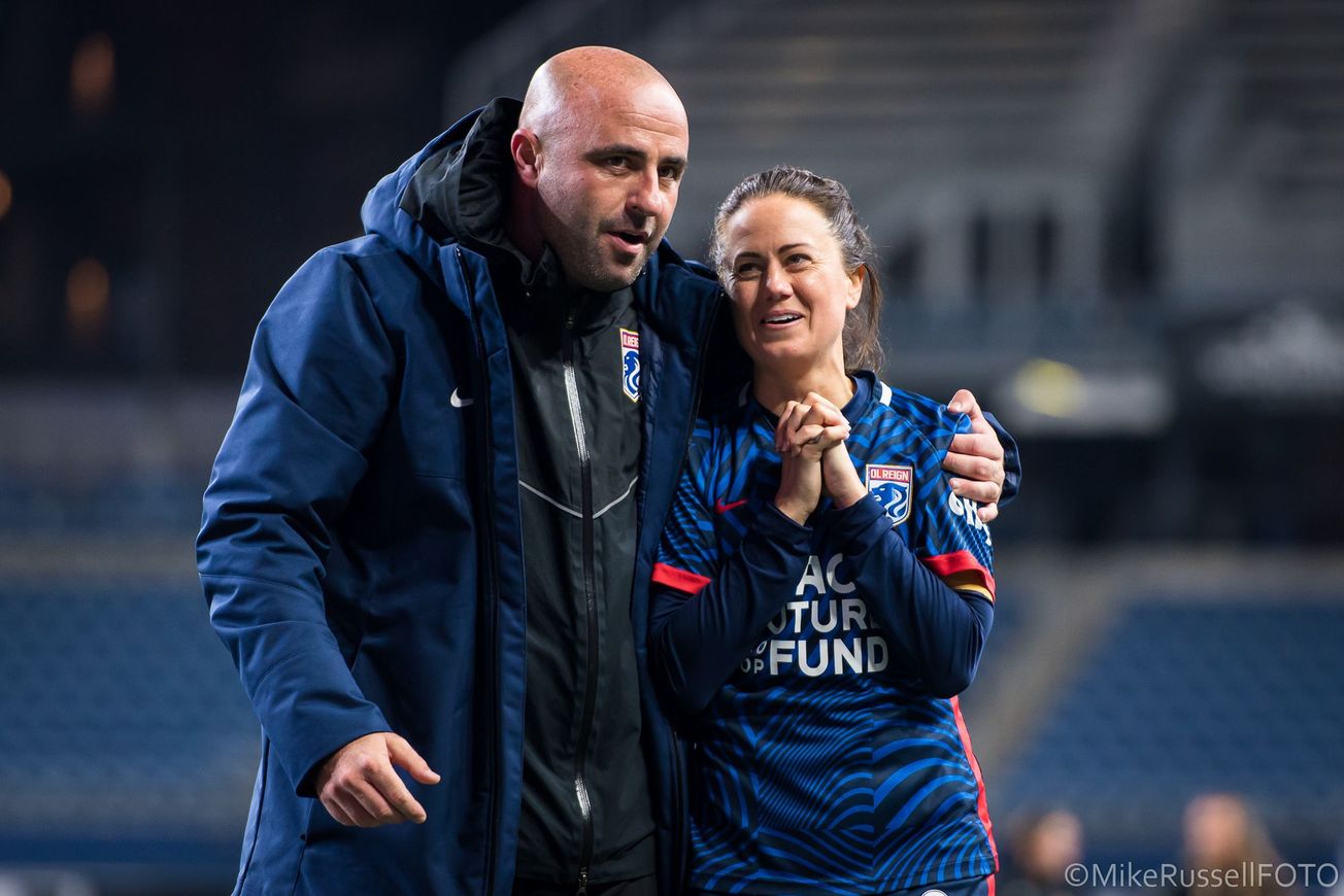 OL Reign assistant coach Scott Parkinson is walking and talking with OL Reign defender Lauren Barnes after a match.