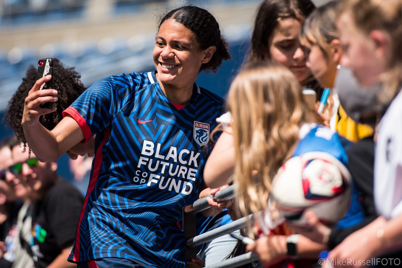 Seattle Reign FC defender Alana Cook takes a selfie with fans after a match.
