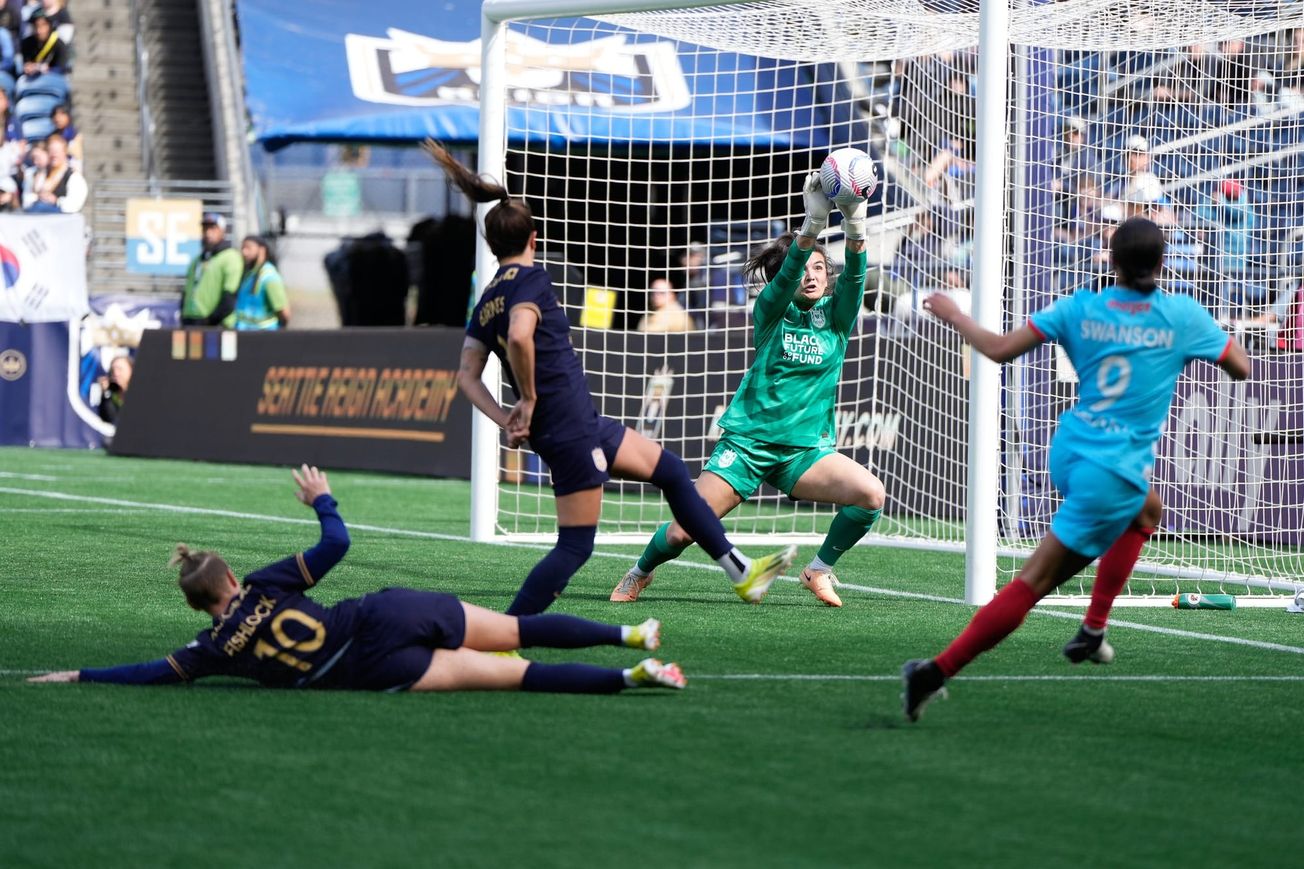 Seattle Reign goalkeeper Laurel Ivory saves a Mallory Swanson shot as defenders fail to stop the ball.