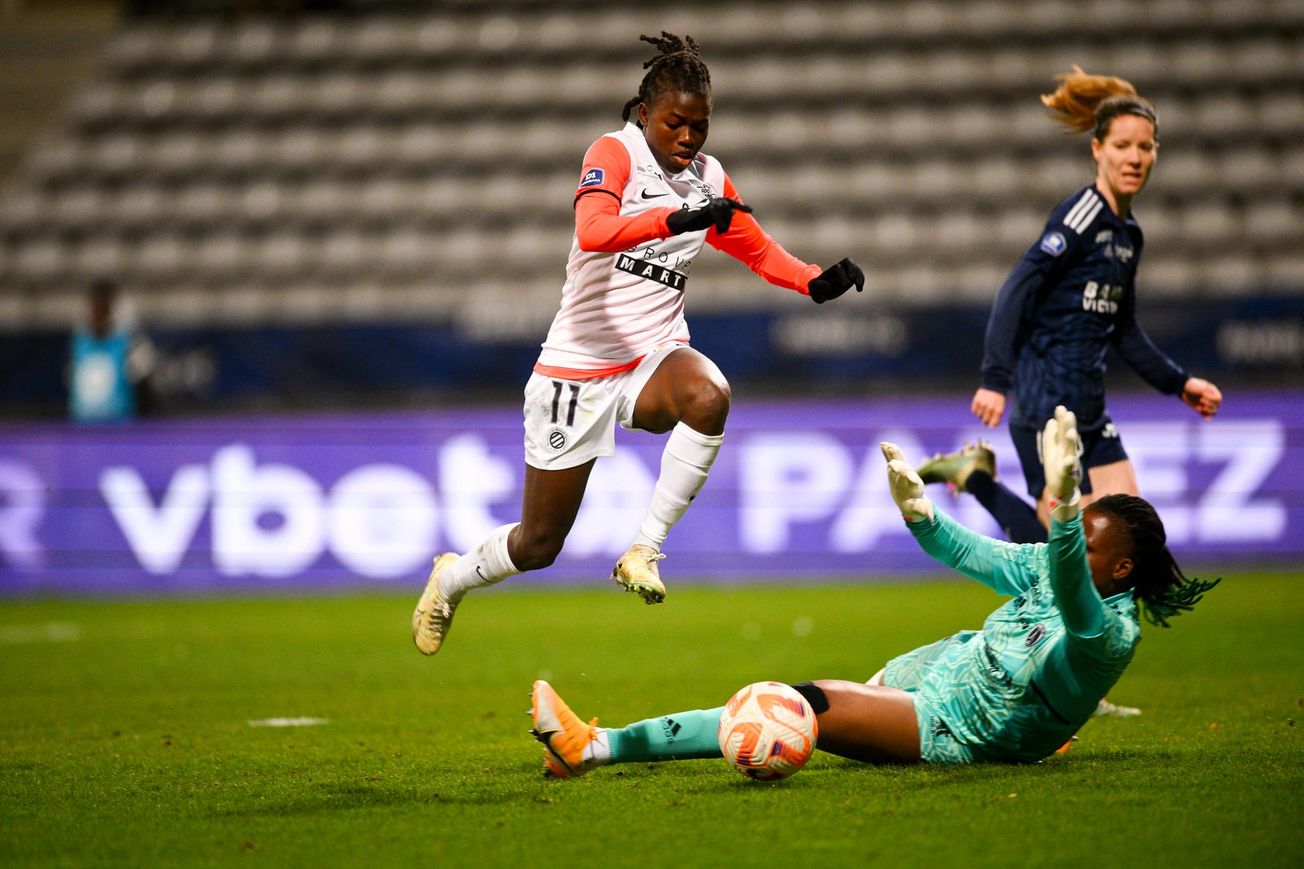 New Seattle Reign FC forward Nérilia Mondésir (in white)jumping over a goalkeeper.