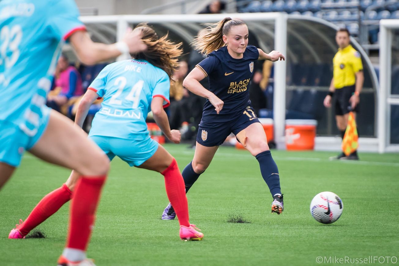 Reign defender Lily Woodham dribbles against two Chicago Red Stars players.