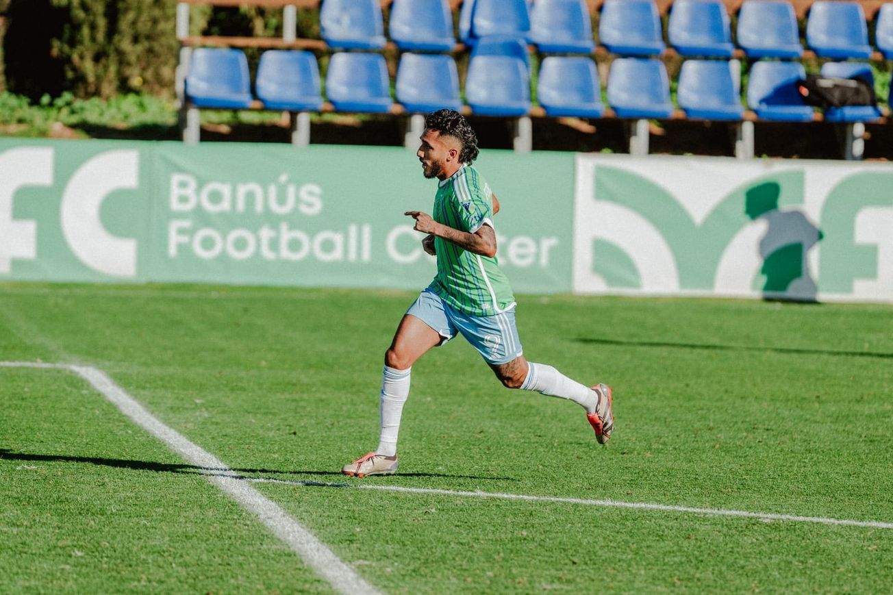 Jesús Ferreira, wearing a green Sounders jersey, light blue shorts, and white socks runs towards goal.