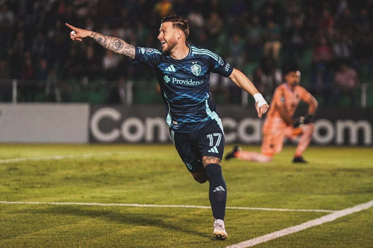 Paul Arriola celebrates as the opposing goalkeeper kneels in the background.