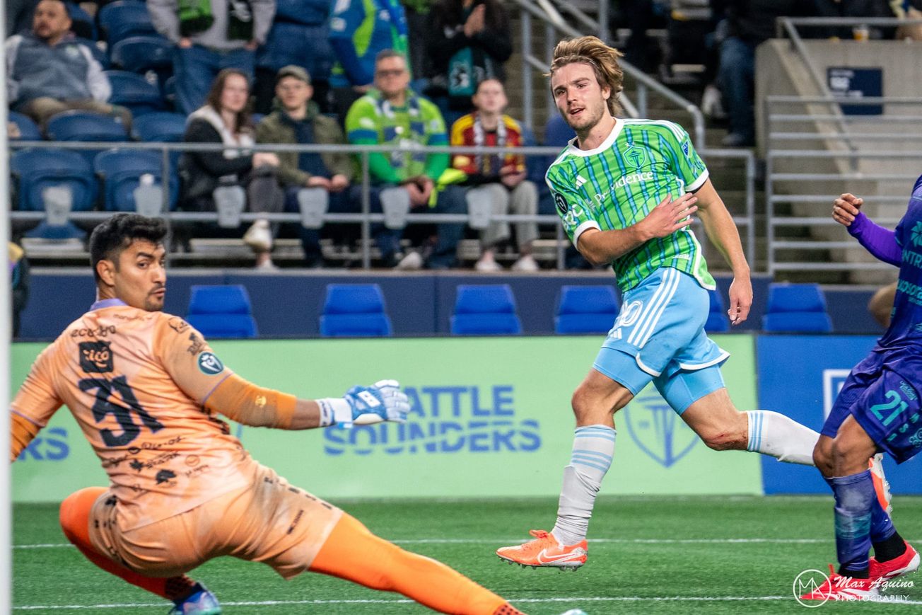 Pedro de la Vega looks on as the goalkeeper looks behind him at the ball going into goal