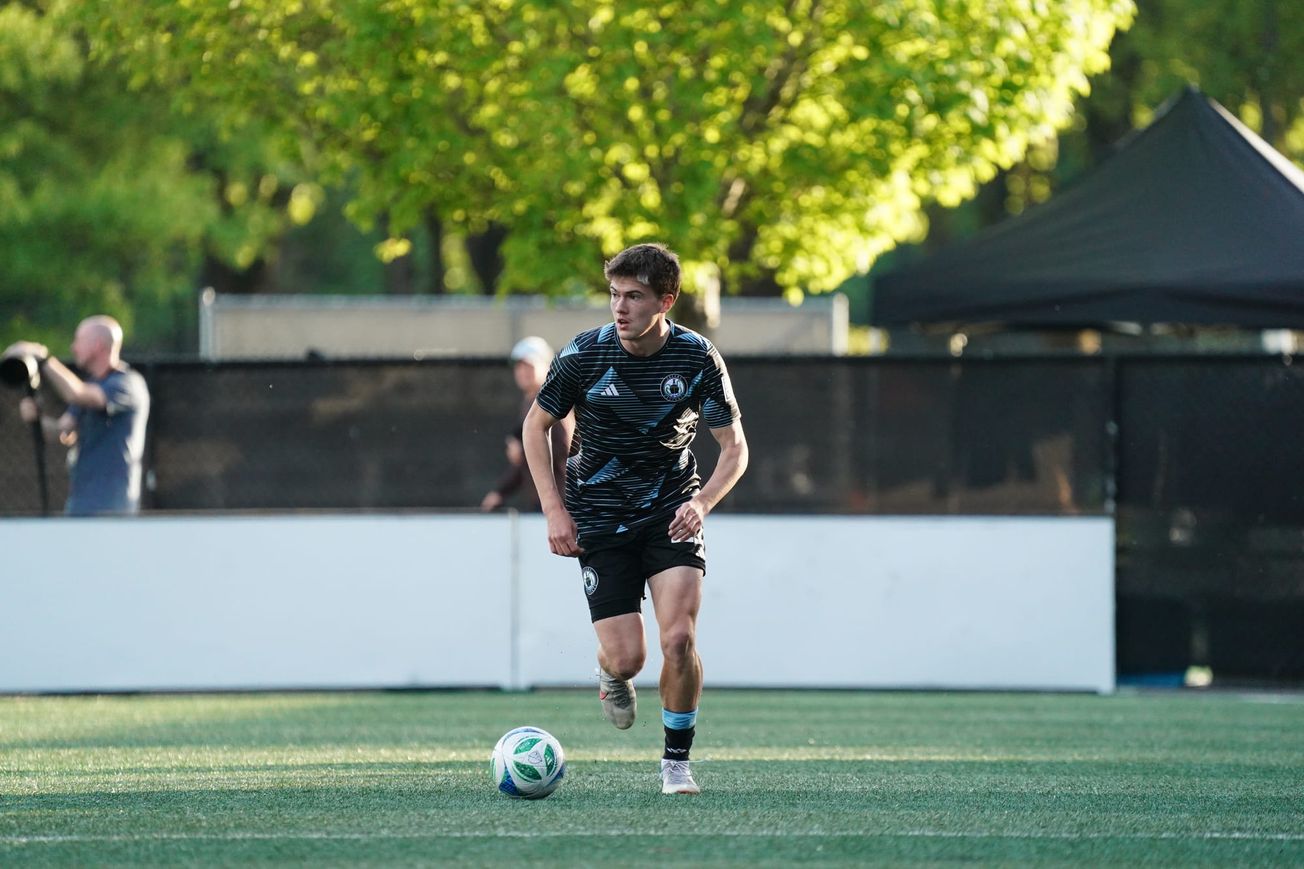 Reed Baker-Whiting running with a ball wearing black Tacoma Defiance kit.