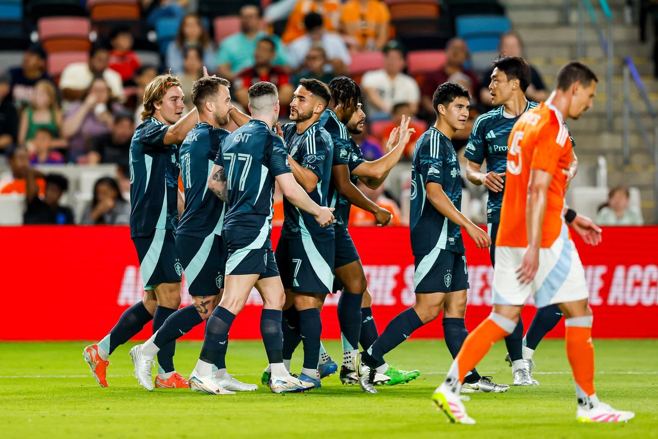 Seattle Sounders players in blue celebrate a goal against the Houston Dynamo.