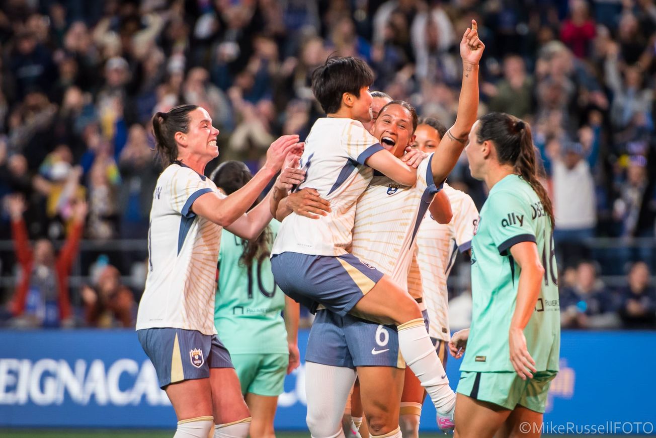 Reign forward Lynn Biyendolo celebrates her goal against KC with teammates Ji So-Yun and Phoebe McClernon in a May 2025 match
