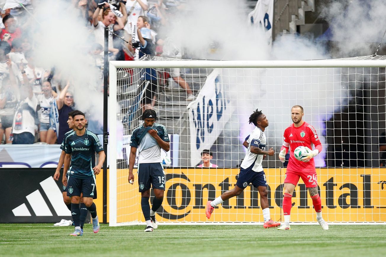 Stefan Frei in a red goalkeeper kit holds the ball in front of goal.