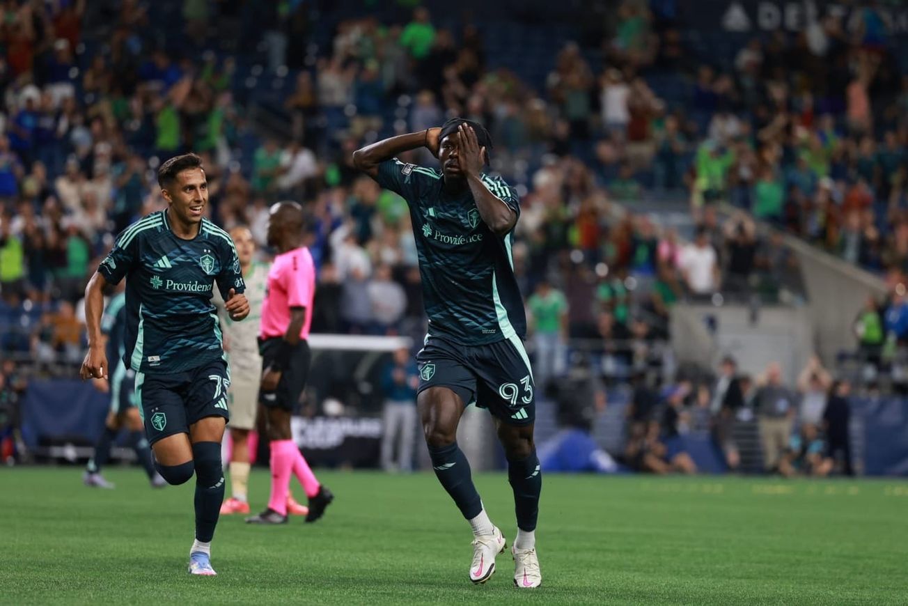 Georgi Minoungou in a blue Sounders jersey celebrates his goal by covering one eye.