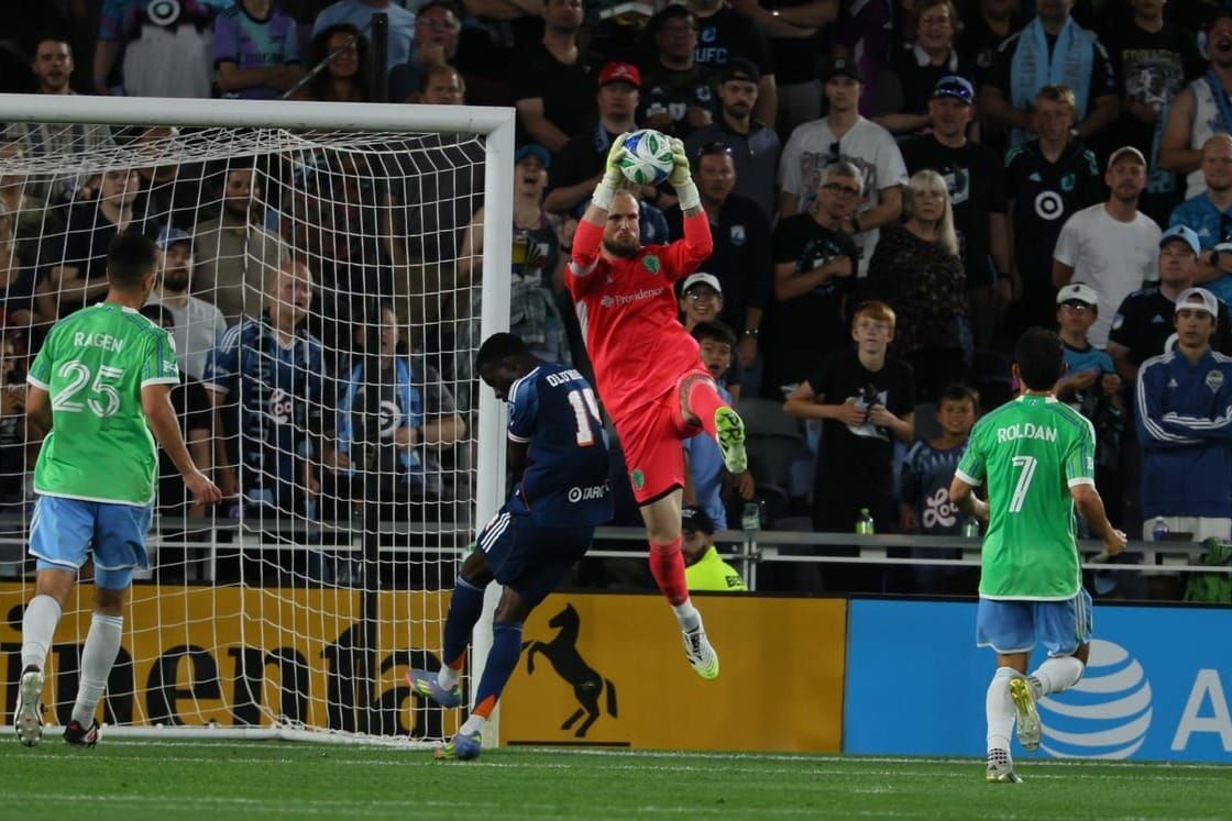 Stefan Frei catches a ball while challenging with a Minnesota player
