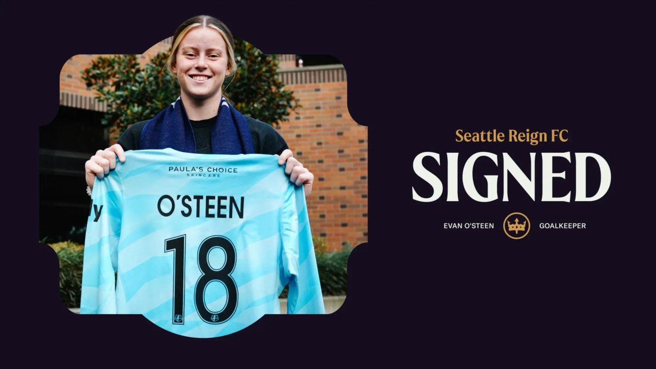 Image of Evan O’Steen holding a Reign goalkeeper jersey with the number 18 and the words ‘Seattle Reign FC - SIGNED’