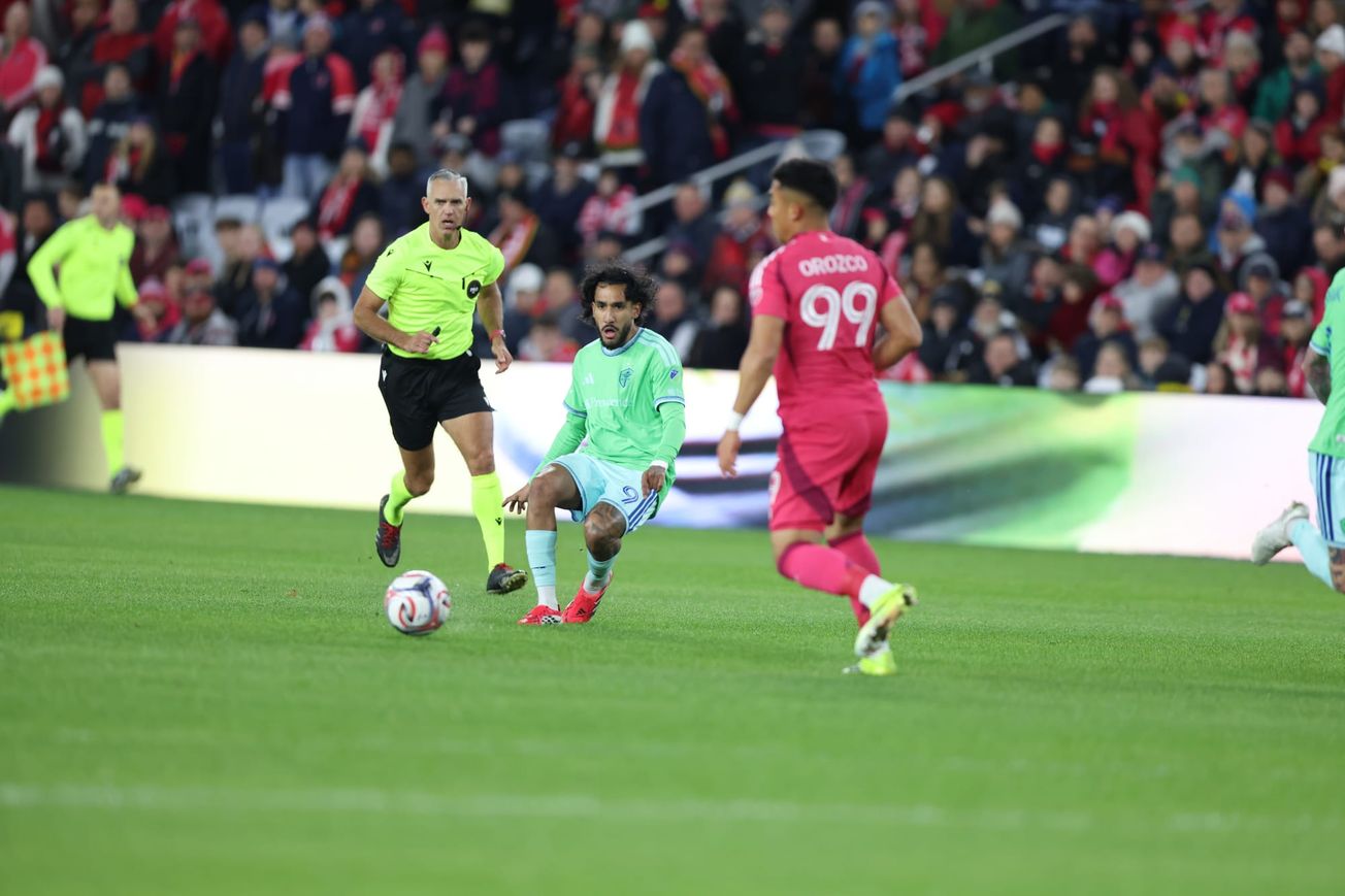 Jesus Ferreira wearing a light green jersey and light blue shorts looks at the ball with a St. Louis player in the foreground