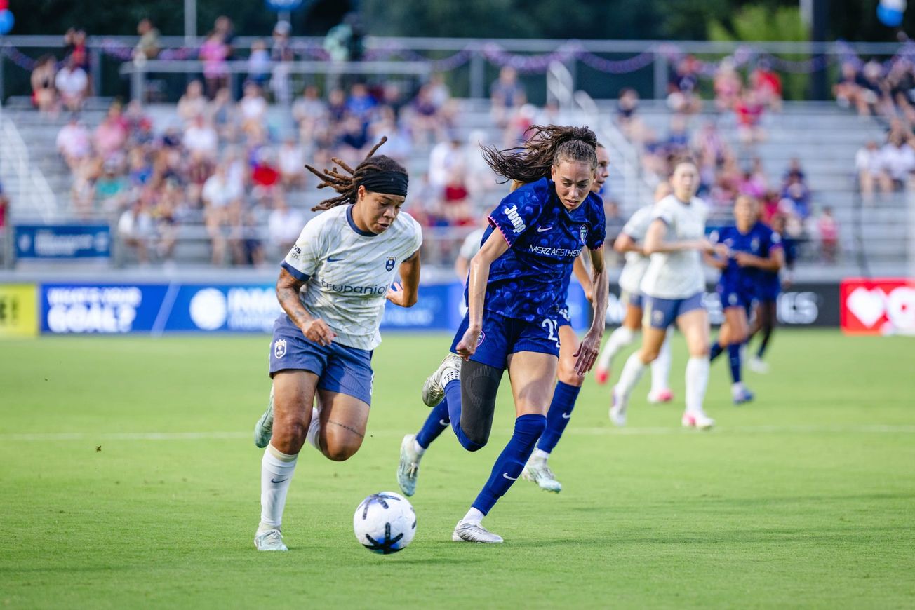 Mia Fishel of the Seattle Reign dribbles against an NC Courage defender in a July 2026 match.