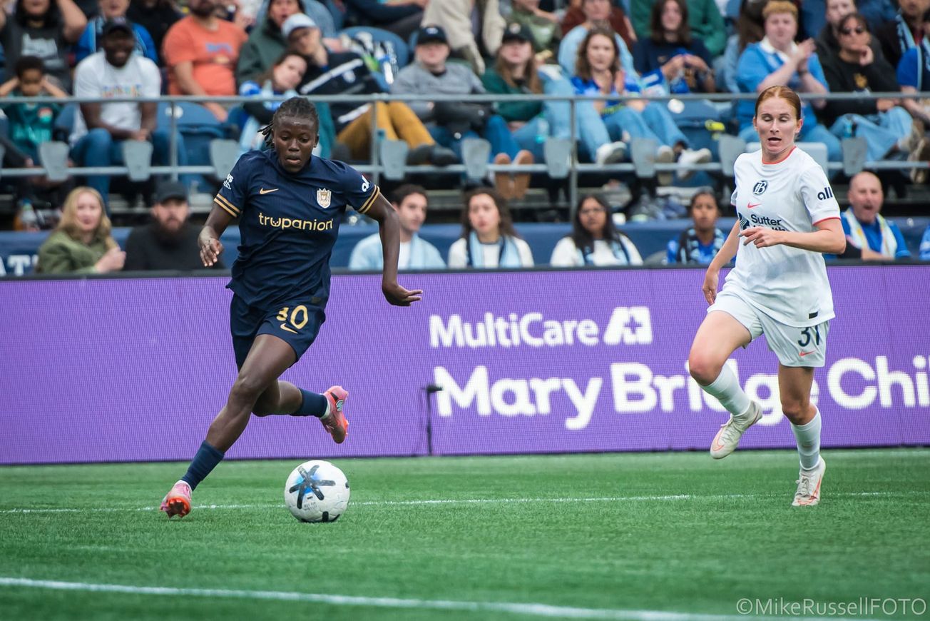 Seattle Reign FC’s Nerilia Mondesir turns the corner on the dribble in the box against Bay FC defender Jenna Nighswonger.