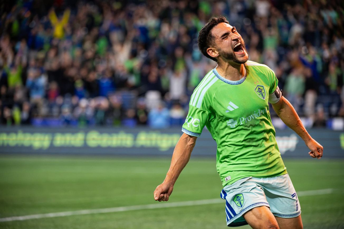 Cristian Roldan in a green Sounders shirt and light blue shorts celebrates the winning goal.