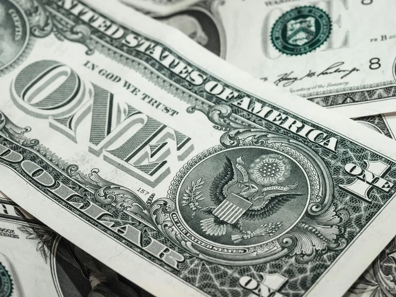 Close-up of overlapping U.S. one-dollar bills showing the Great Seal. 