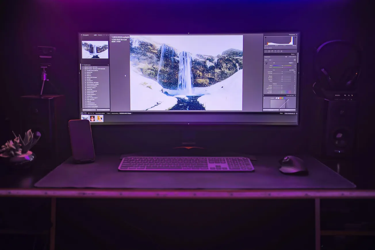Ultra-wide monitor displaying waterfall photo editing software on a modern desktop setup with keyboard and mouse.