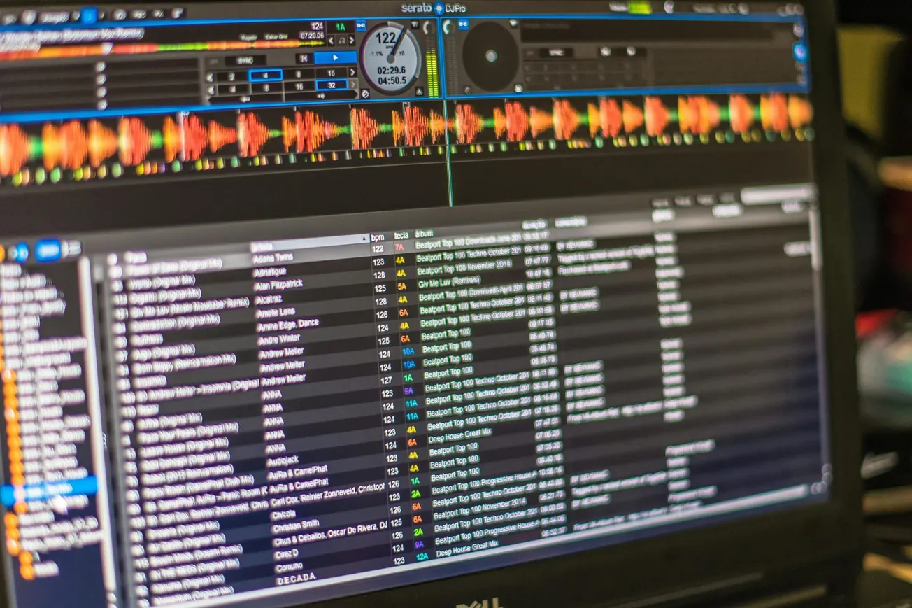Close-up of an audio software screen displaying a list of music tracks on the lower half and colorful waveforms on the top.