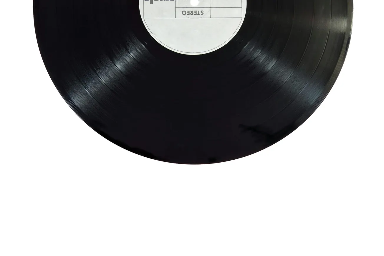 Close-up of a black vinyl record with a blank white label marked "Stereo." The grooves are visible, reflecting a nostalgic musical vibe.