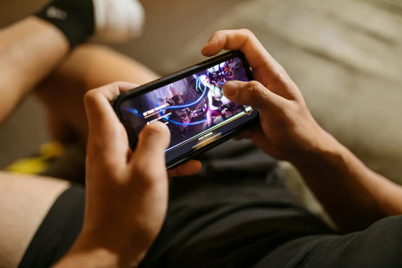 Person holds a smartphone, intensely playing a vibrant video game.