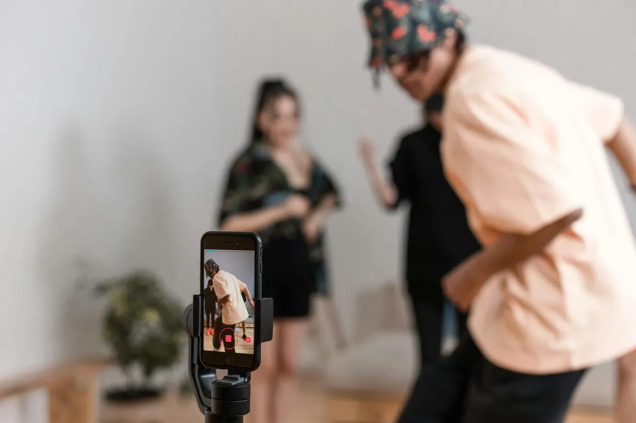 Smartphone on tripod recording people dancing for a social media video indoors.