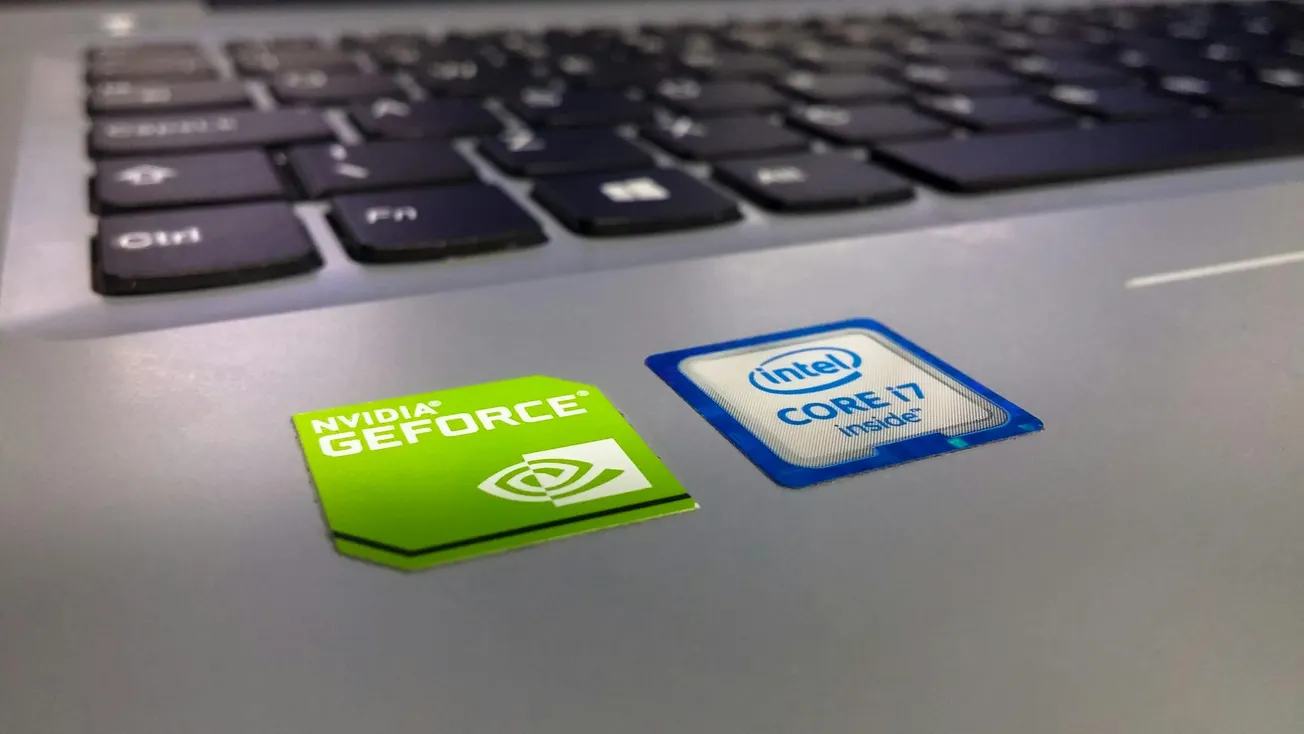 Close-up of a laptop keyboard showing Nvidia GeForce and Intel Core i7 stickers on the silver surface, reflecting a tech-focused ambience.