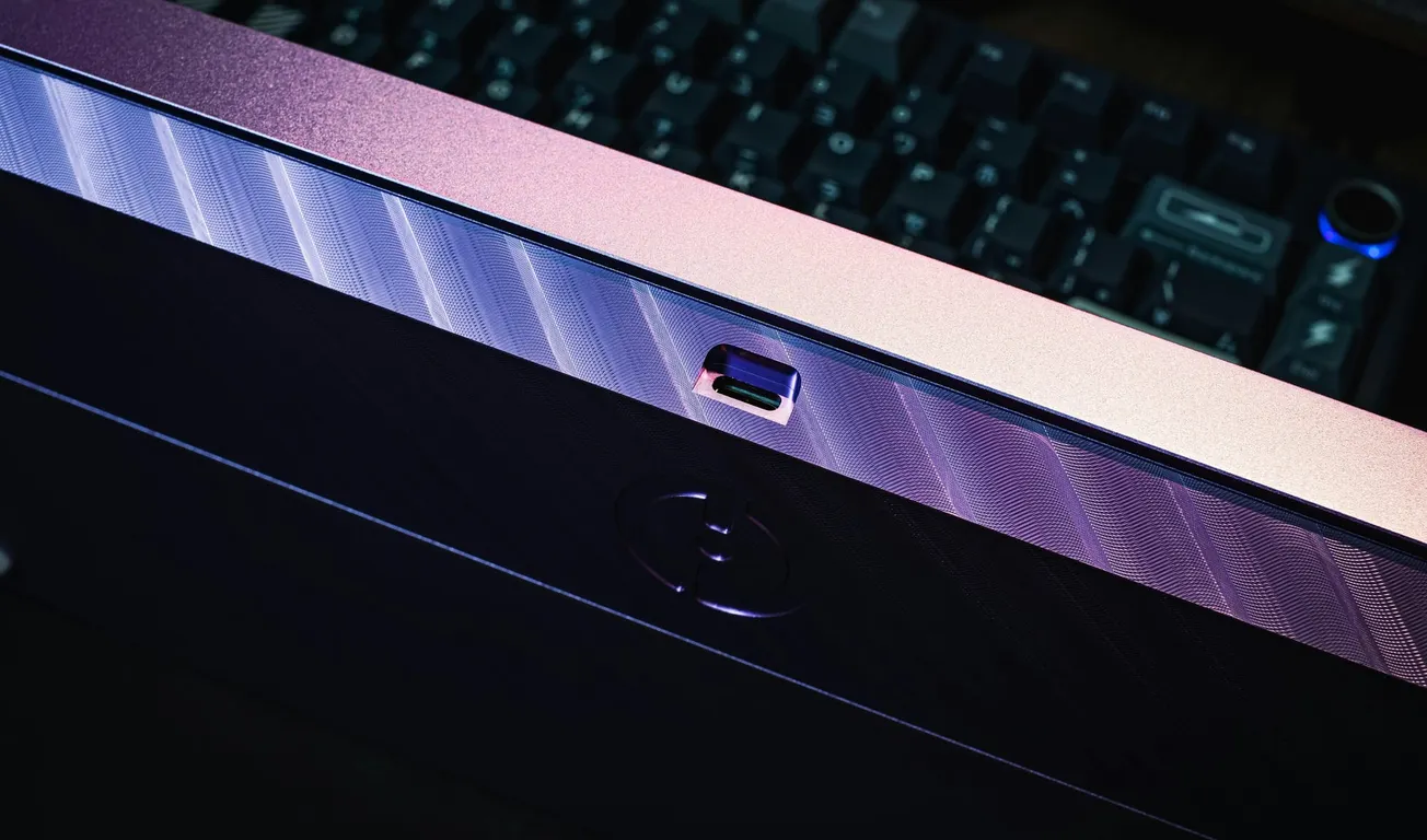 Close-up of a metallic purple USB-C port on a device, with a blurred keyboard in the background. The lighting creates a sleek and modern look.