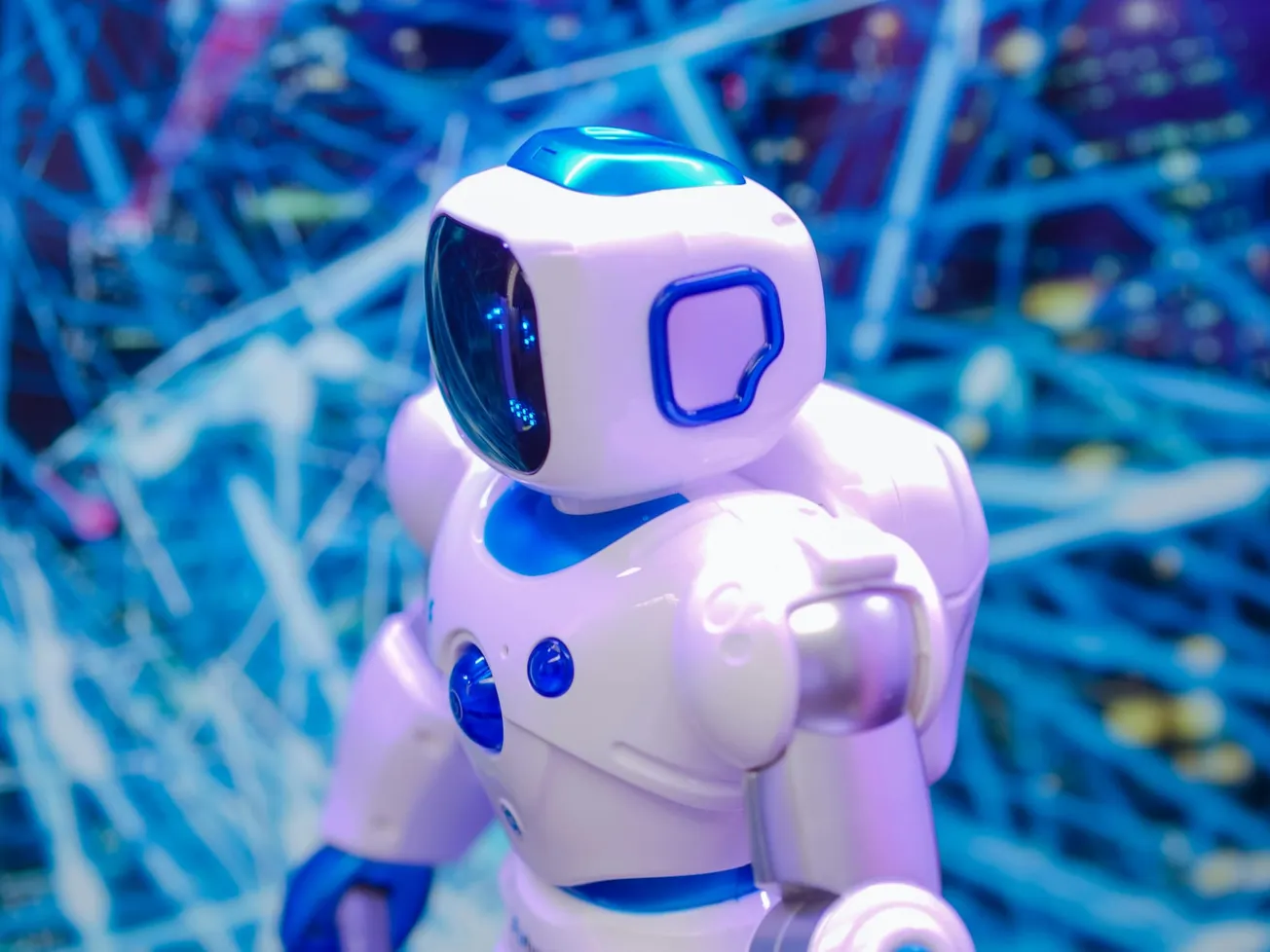 A futuristic white and blue robot with a glossy helmet stands in front of a vivid, abstract digital network background. The scene is vibrant and high-tech.
