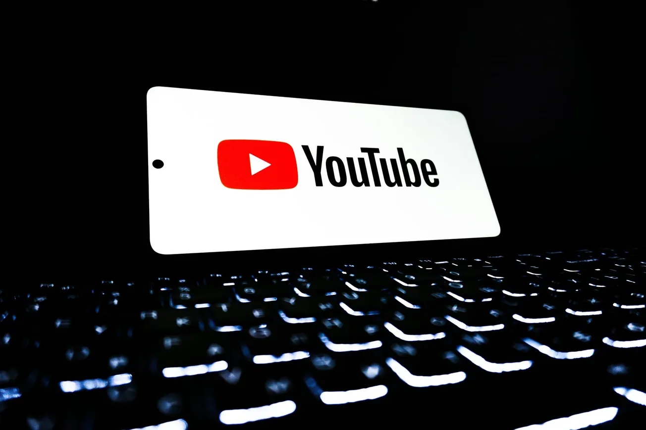 Bright YouTube logo displayed on a screen above a glowing keyboard in a dark environment, creating a futuristic and tech-focused vibe.